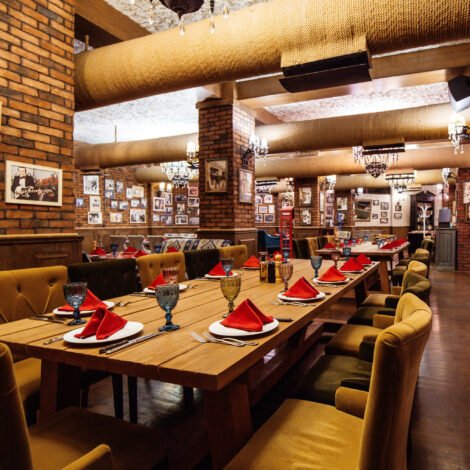 a restaurant hall with red brick walls wooden tables and pipes in the ceiling